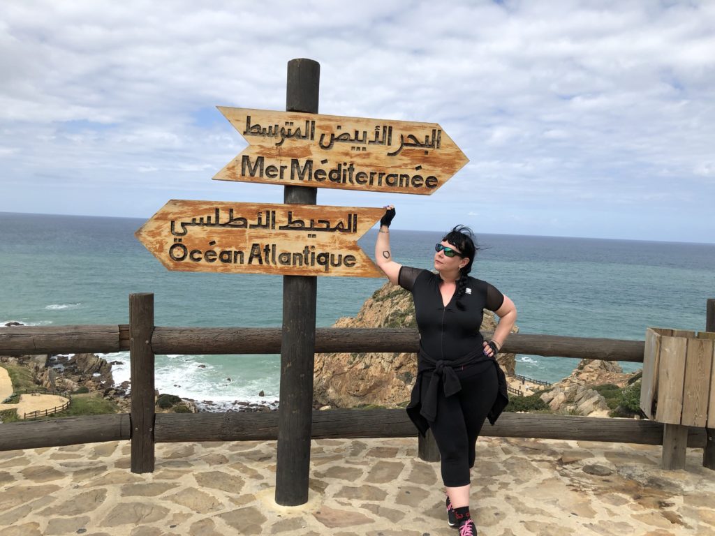 Liisa poses in Tangiers with signs for the Atlantic Ocean and Mediterranean Sea.